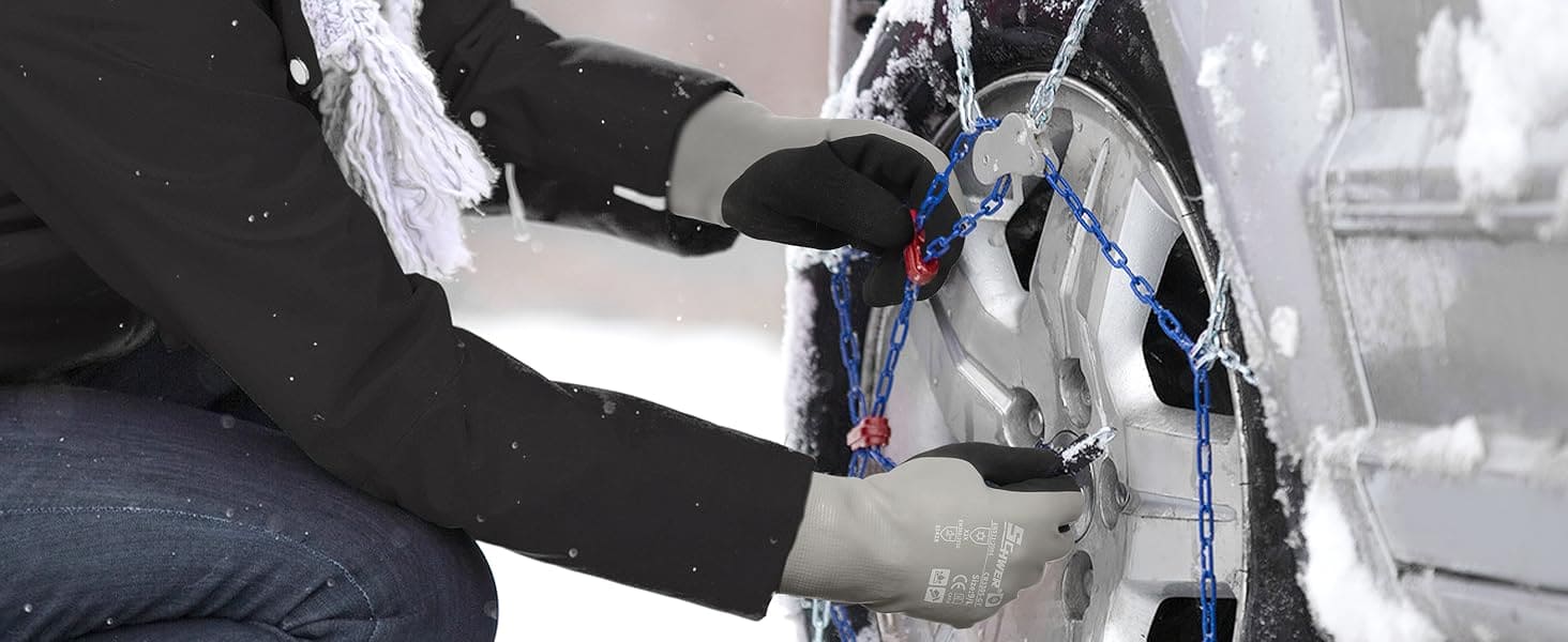 Person securing a tire chain on a vehicle's wheel in snowy conditions
