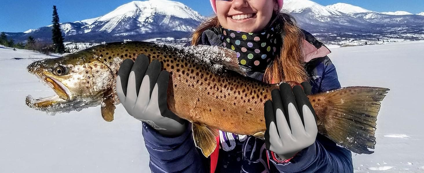 Person holding a large brown trout in a snowy landscape with mountains in the background