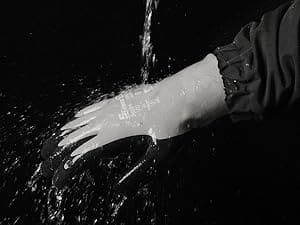 Hand wearing a glove washing in water with a black background