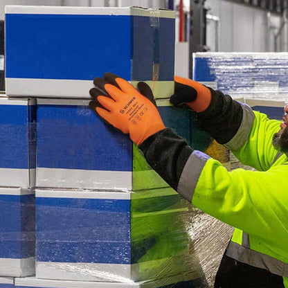 Worker in high-visibility jacket wearing orange waterproof winter gloves handling stacked blue and white boxes in warehouse