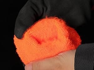 Hand holding an orange towel with a black background