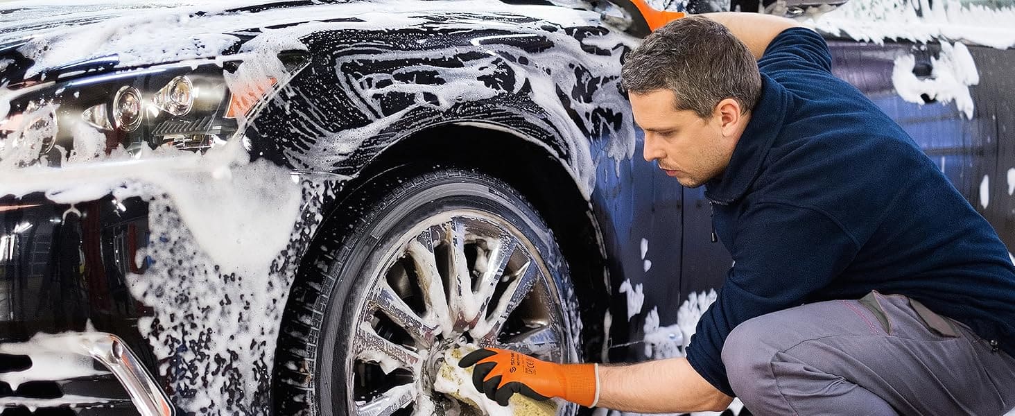 Person washing a car with soapy water and soap suds on the vehicle.
