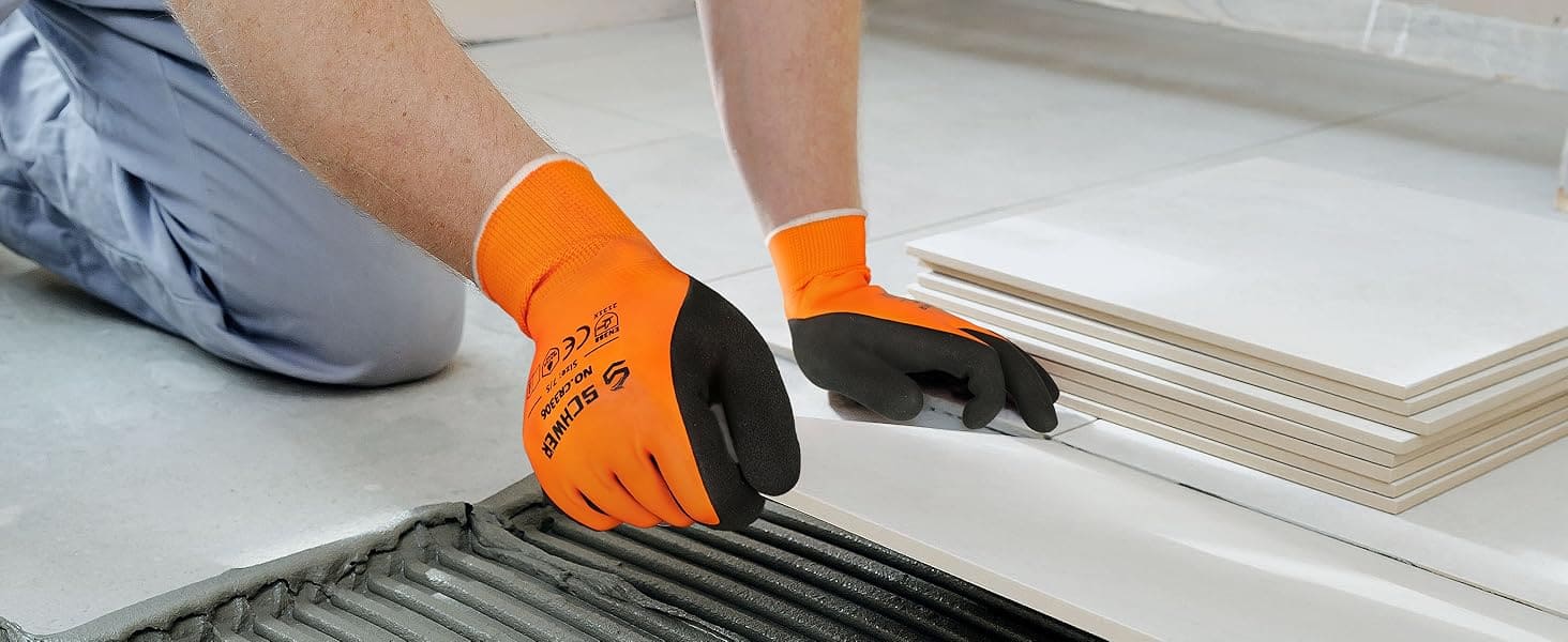 Person installing tiles with gloves on, focusing on the task.
