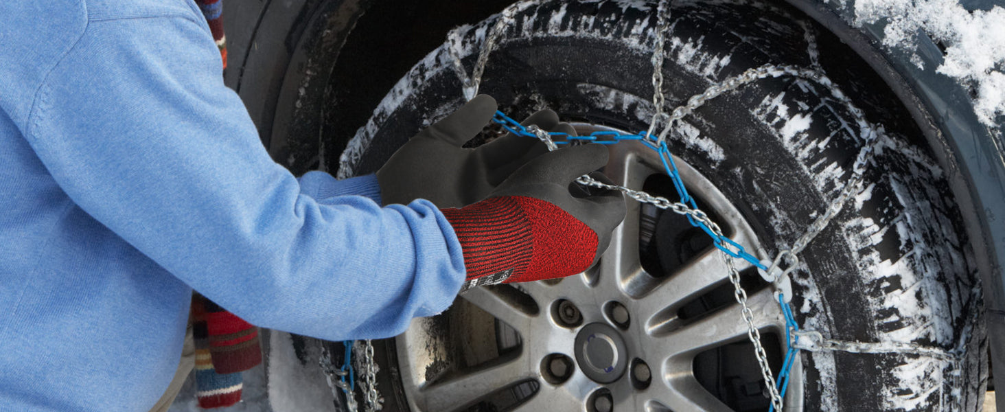 Person installing snow chains on a car tire in snowy conditions