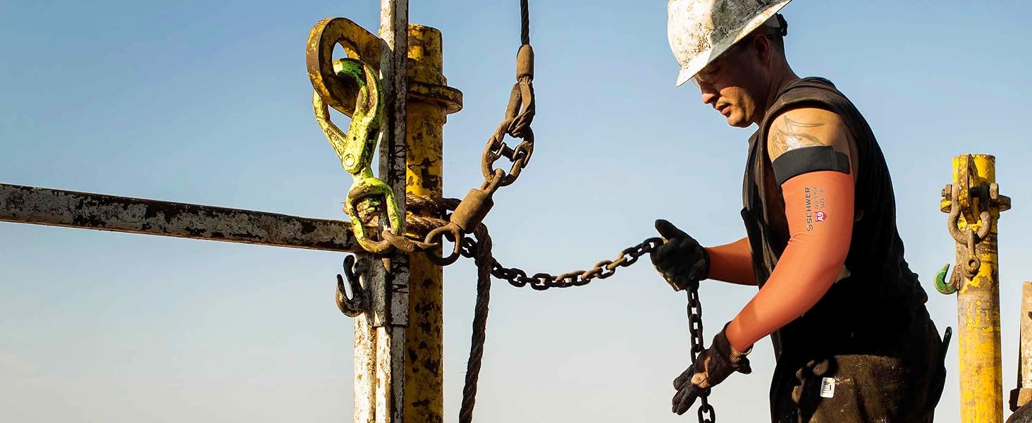 Person working with drilling equipment against a clear blue sky