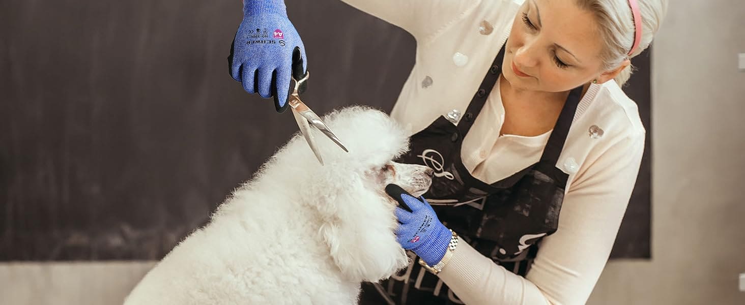 Person grooming a white dog with gloves on, wearing an apron.