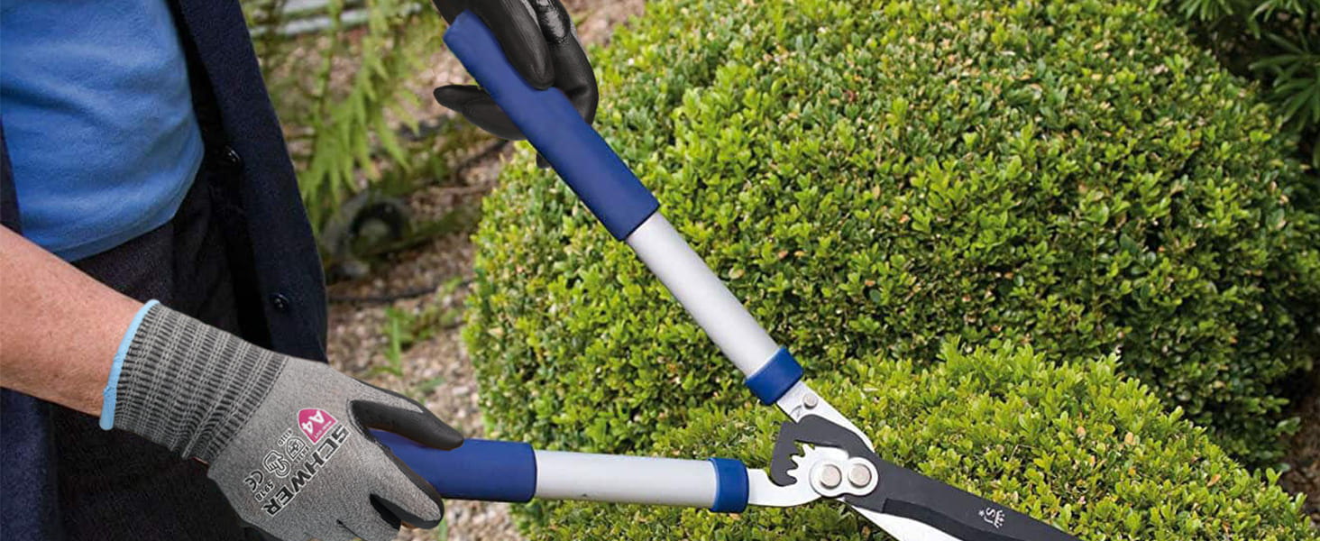 Person using garden shears to trim a bush with a blurred background